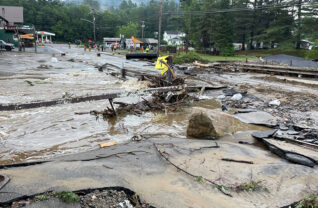 A one-day, once-in-a-century storm, typical of the extreme weather attributed to climate change, took hundreds of thousands of dollars away from the Adirondack Park’s tourism economy in July. Above: the travel corridor’s important intersection at State Route 30 and Route 28N in Long Lake was open only to emergency vehicles.