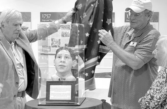 Frank and Rosemary Pusateri, who commissioned the facial reconstruction of a Revolutionary War soldier whose remains are interred at the new war memorial, unveil the model with Lake George Battlefield Alliance board member Mark Silo.